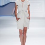 White super piqué sleeveless peplum coat with oversized hood and cutout pockets over white textured silk slip dress